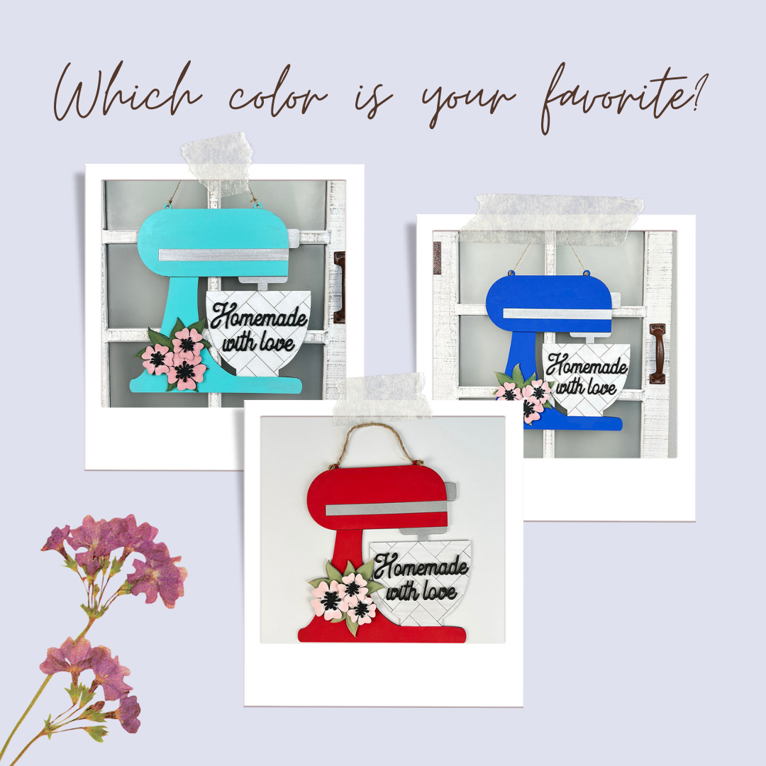 The Kitchen Mixer Wall Hanger DIY Home Decor Craft Kit by Janet's Craft Corner features three paper cutouts of stand mixers in blue, teal, and red with "Homemade with Love" signs. Adorned with pink flowers on a polaroid-style backdrop, it asks "Which color is your favorite?" to enhance kitchen charm.