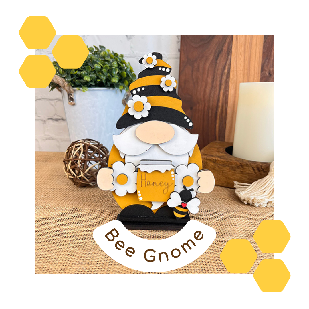 The Bee Gnome Shelf Sitter DIY craft kit by Janet's Craft Corner is a delightful addition to your farmhouse decor. Featuring a bee-themed gnome with a honey pot, hexagonal designs, and a backdrop of candle, plant, and woven ball on burlap, it sparks creativity with its inviting "Bee Gnome" label.