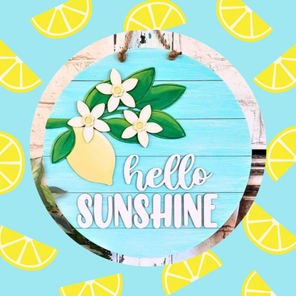 The "Hello Sunshine Lemon Round Sign" from Janet's Craft Corner is a DIY seasonal home decor craft kit. This charming piece features lemons, white flowers, and scattered yellow slices on a blue background, encapsulating sunny DIY charm.