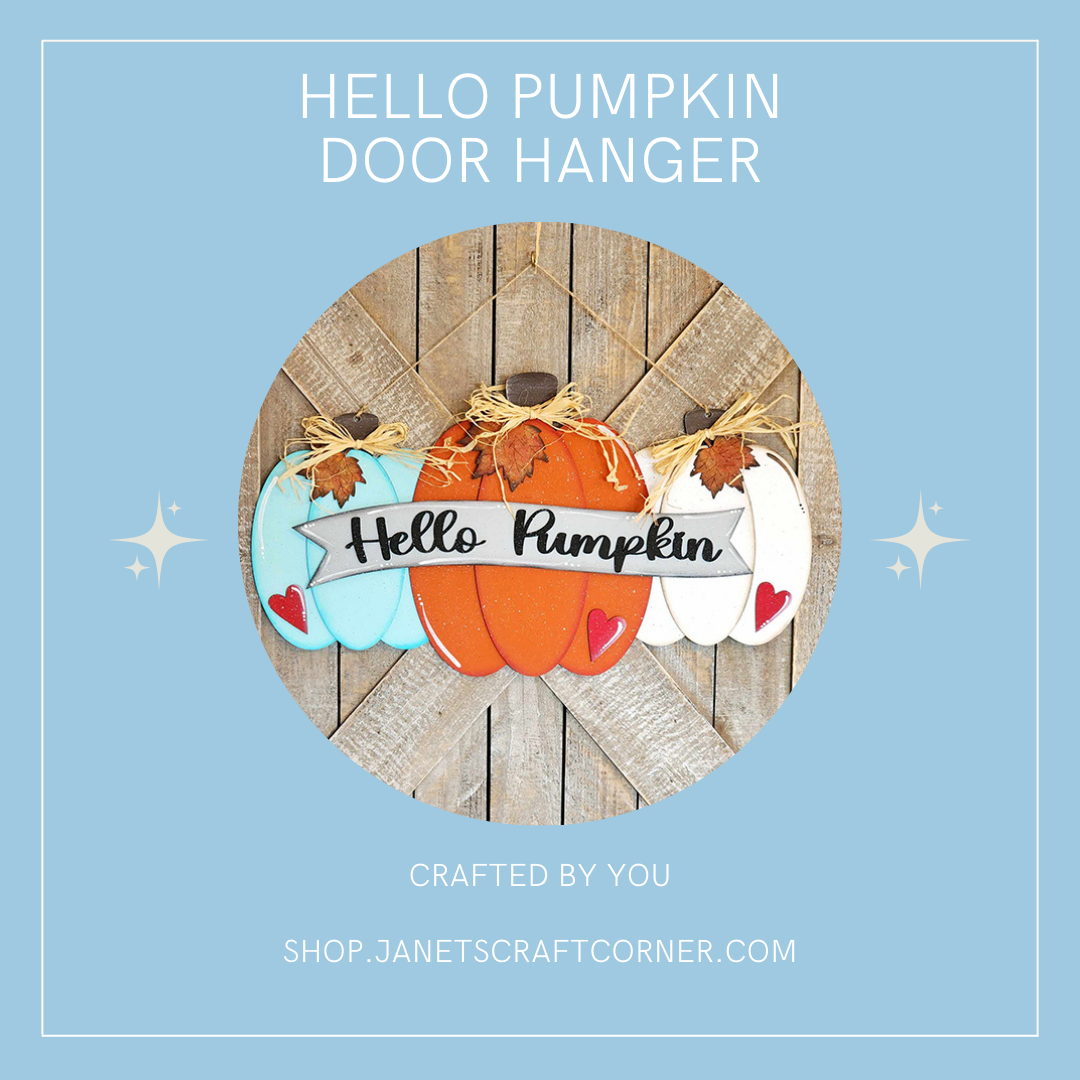 An image of the Hello Pumpkin Door Hanger from Janet's Craft Corner shows three hand-painted pumpkins in blue, orange, and white with "Hello Pumpkin" on a banner. The rustic wooden backdrop sits within a blue square frame, making it an ideal addition to your DIY seasonal home decor collection.