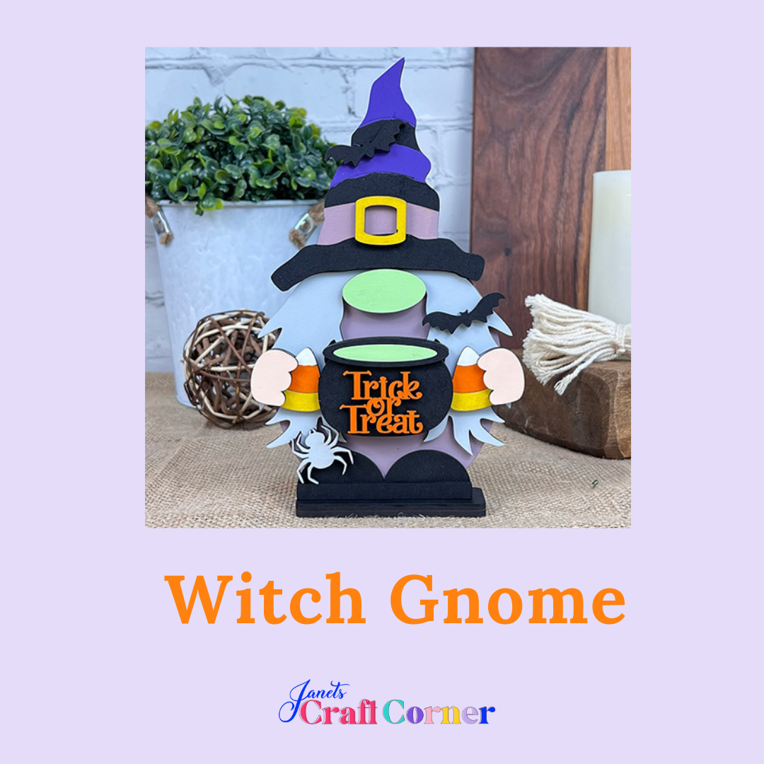 Janet's Craft Corner presents the Witch Gnome Shelf Sitter DIY kit, featuring a gnome with a purple hat and green face holding a "Trick or Treat" cauldron. Ideal seasonal home décor, it includes Halloween decorations for display on a wooden table.