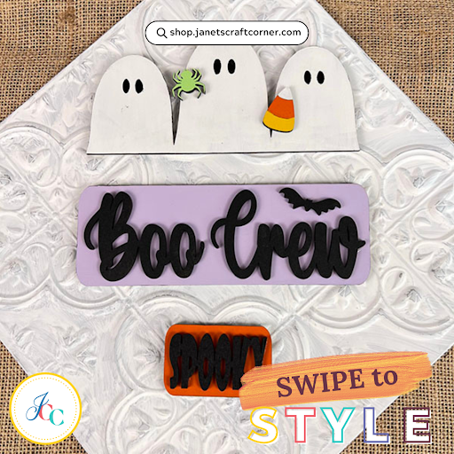 Introducing the "Boo Crew" Interchangeable Insert from Janet's Craft Corner: A DIY seasonal craft kit featuring three ghost cutouts, a green spider, candy corn, a bat motif "Boo Crew" sign, and an orange "Spooky" plaque. Perfect for your Halloween decor. Text reads "SWIPE to STYLE." Logo at bottom.