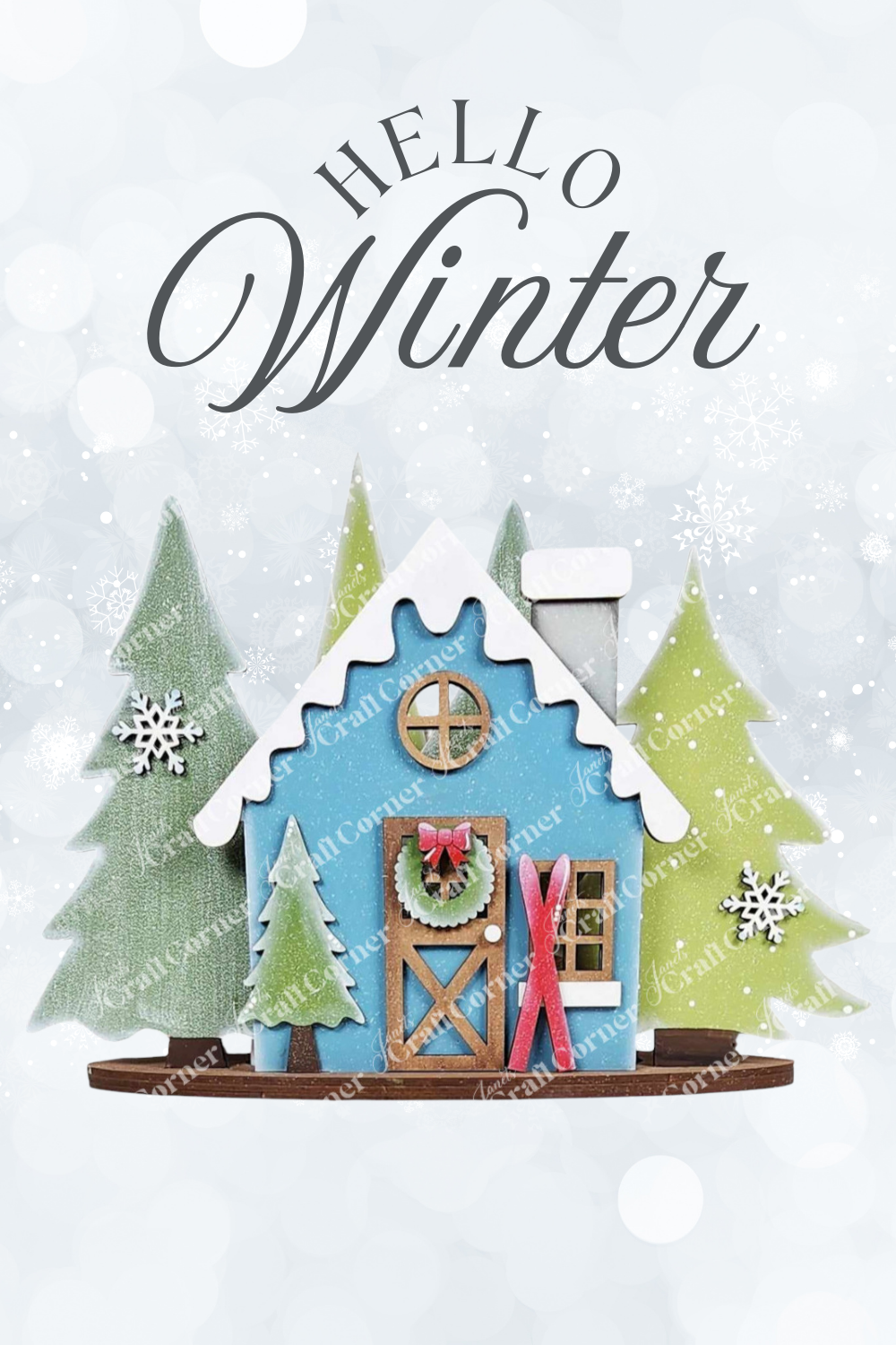 Illustration of a blue cabin with snow-covered roof, pine trees, and wreath on the door; red skis are beside it. "Hello Winter" text adds charm to this cozy scene. Part of Janet's Craft Corner's Winter Cabin Decor Set - DIY seasonal home decor craft kit, 1 set includes 6 pieces.