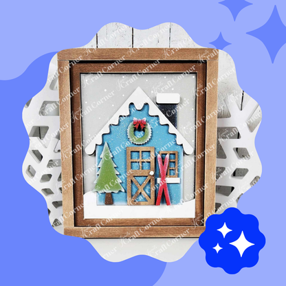 A framed depiction of cozy winter nights showcases a snowy cabin with a blue background, a wreath, red skis, and a green pine tree on a snowflake-shaped backdrop—just like Janet's Craft Corner’s Winter Cabin Interchangeable Farmhouse Sign DIY craft kit.