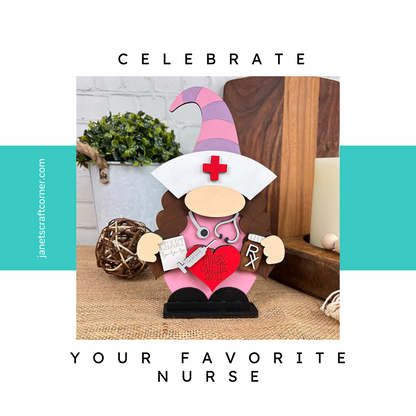 The Nurse Gnome Shelf Sitter from Janet's Craft Corner features a wooden figure in a pink and purple hat with a nurse cap, holding a heart-shaped "Nurse Gnome Clinic" sign, perfect as farmhouse decor to celebrate your favorite nurse.