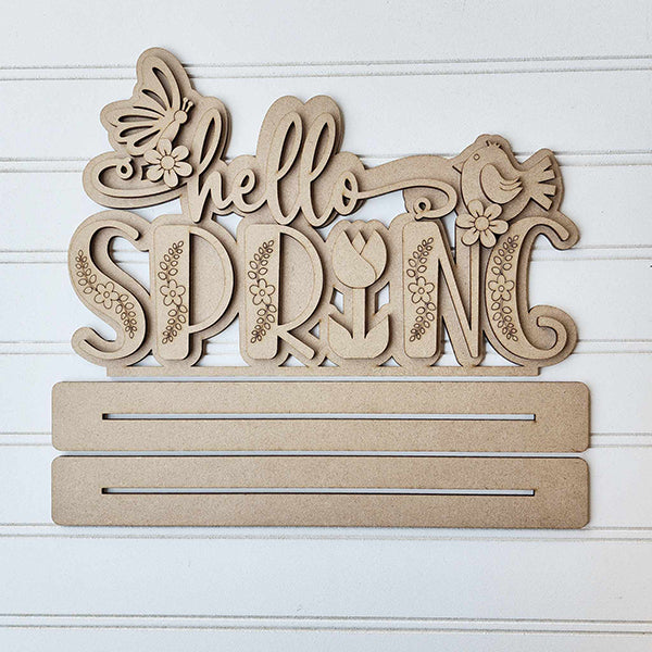 Janet's Craft Corner presents the "Hello Spring" Word Art Standing Shelf Sitter, a DIY wooden cutout featuring decorative script with butterfly, bird, and flower accents. Customize your home décor piece with additional elements using two slots provided.