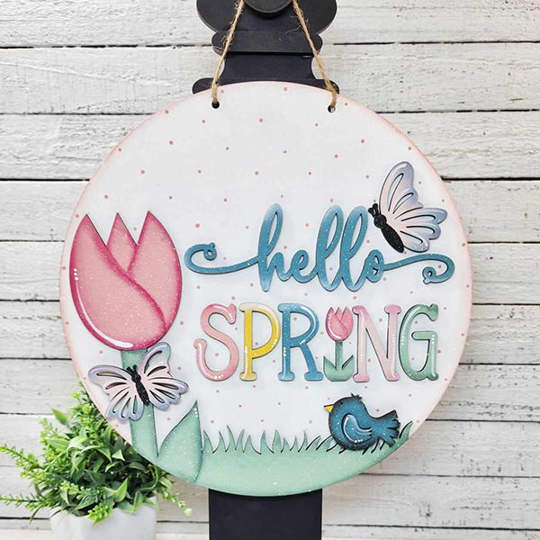 Add a touch of seasonal charm to your home's décor with Janet's Craft Corner's "Hello Spring" Round Door Hanger. This delightful DIY kit features vibrant letters, a tulip, butterflies, and a bird resting on grass. It easily hangs against a wooden backdrop with a small plant nearby, making it the perfect addition for welcoming springtime.