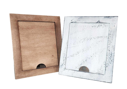 Against a black background, two empty photo frames are displayed side by side. The left frame is crafted from light brown wood, while the right frame belongs to Janet's Craft Corner and is named the "Simple Farmhouse Frame for Interchangeable Signs," showcasing a white weathered finish ideal for farmhouse decor. Both frames feature a small semicircular cutout at the bottom.