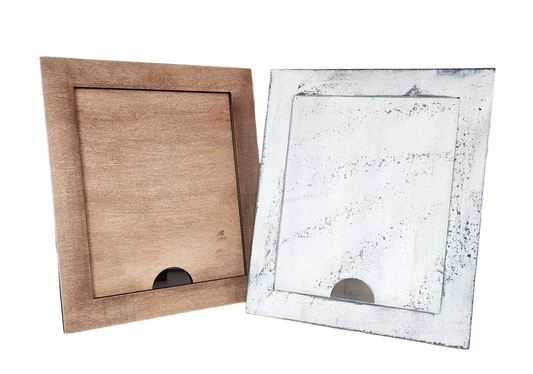 Against a black background, two empty photo frames are displayed side by side. The left frame is crafted from light brown wood, while the right frame belongs to Janet's Craft Corner and is named the "Simple Farmhouse Frame for Interchangeable Signs," showcasing a white weathered finish ideal for farmhouse decor. Both frames feature a small semicircular cutout at the bottom.