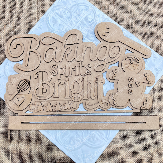 Discover the charming "Baking Spirits Bright" Shelf Sitter from Janet's Craft Corner. This DIY home decor craft kit includes a hand-painted wooden decoration set against a burlap background, featuring the phrase "Baking Spirits Bright" alongside whimsical images of a whisk, spoon, and gingerbread person. It's perfect for adding a touch of festive creativity to your home décor.