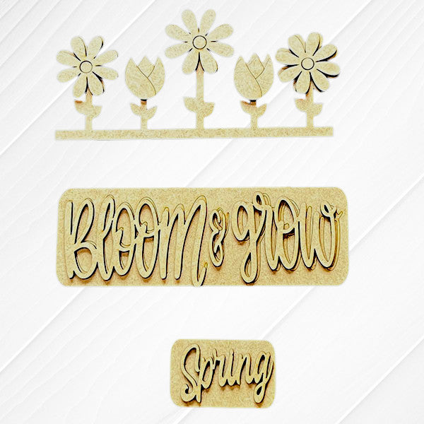 Wooden cutouts on a white background from Janet's Craft Corner. The Spring Blooms Interchangeable Insert features four flowers, "Bloom & Grow" in cursive, and "Spring" in smaller cursive. Ideal for DIY hand-painted home decor set.