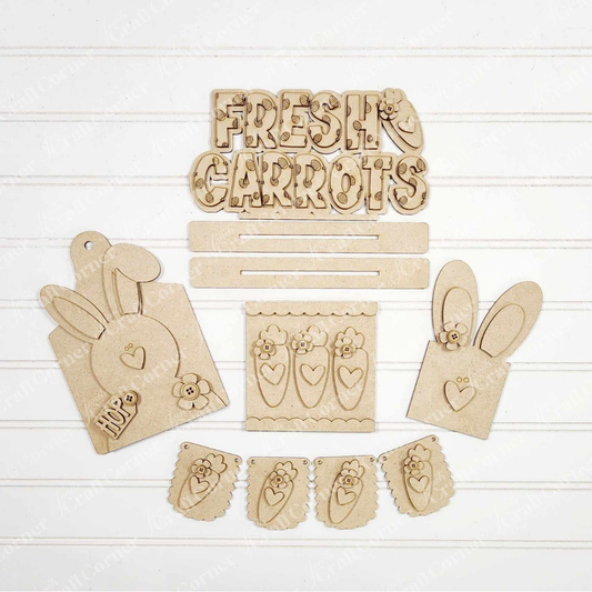 The Bunnies & Carrots Decor Set from Janet's Craft Corner includes hand-painted cutouts like bunnies with hearts, a "Fresh Carrots" sign with florals, and a decorative banner. This DIY craft kit adds a personalized touch to your home décor.