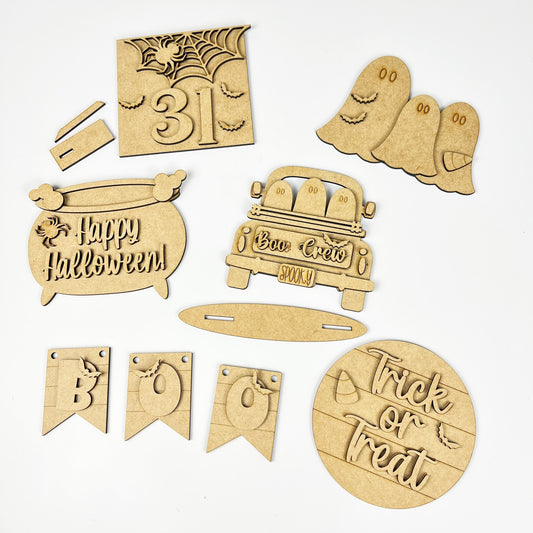 The Boo Crew Decor Set by Janet's Craft Corner is a DIY seasonal home decor kit with 6 wooden cutouts: "31" with bat, ghosts, a "Happy Halloween" cauldron, "Boo Crew" truck, festive "BOO" flags, and a playful "Trick or Treat" circle—perfect for your tier tray creativity.