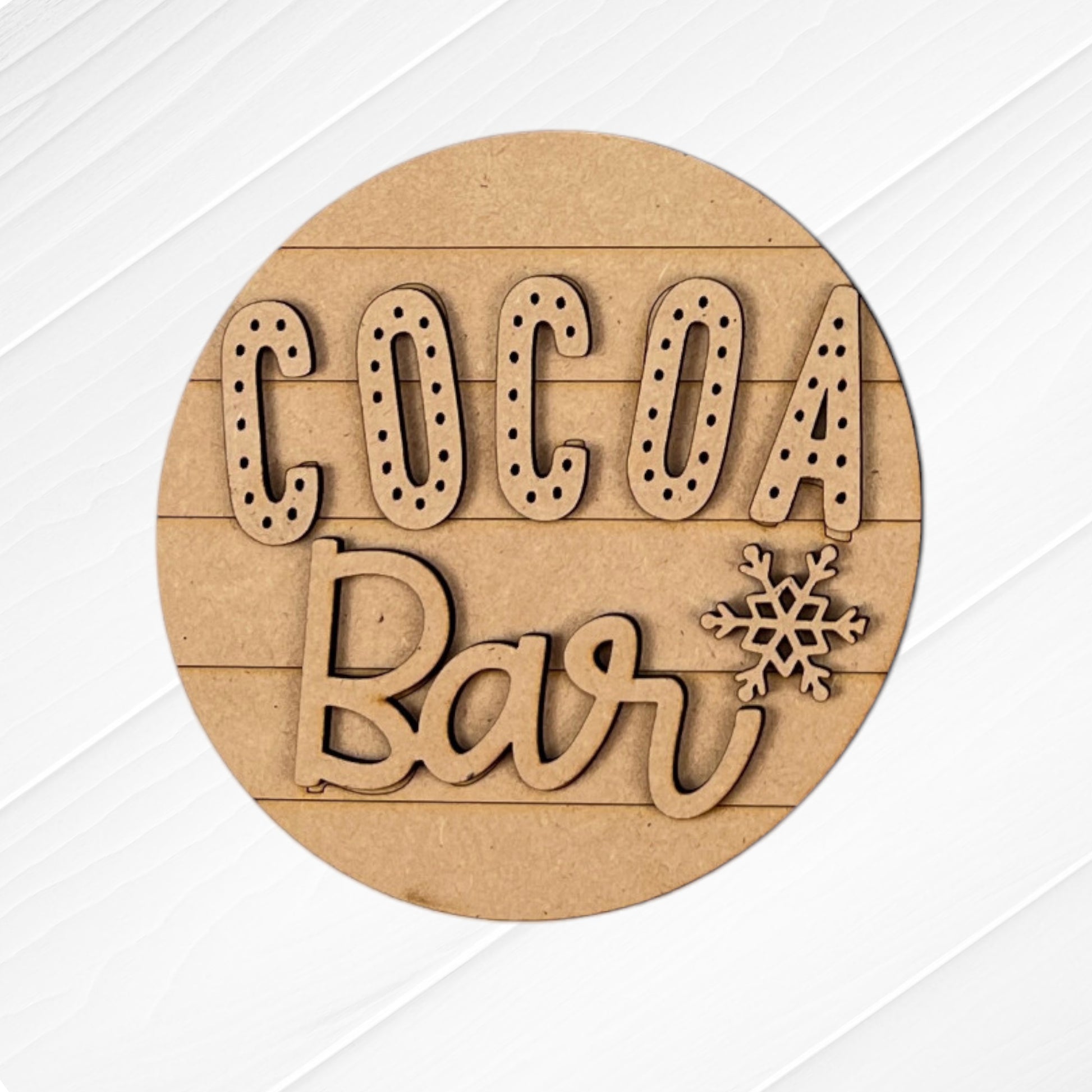 Add a cozy touch to your home with this round wooden sign featuring "Cocoa Bar" and a snowflake design from the Cup of Cheer Hot Cocoa Decor Set by Janet's Craft Corner. Crafted with light wood texture and horizontal slats, it's a perfect addition to your DIY home decor efforts.