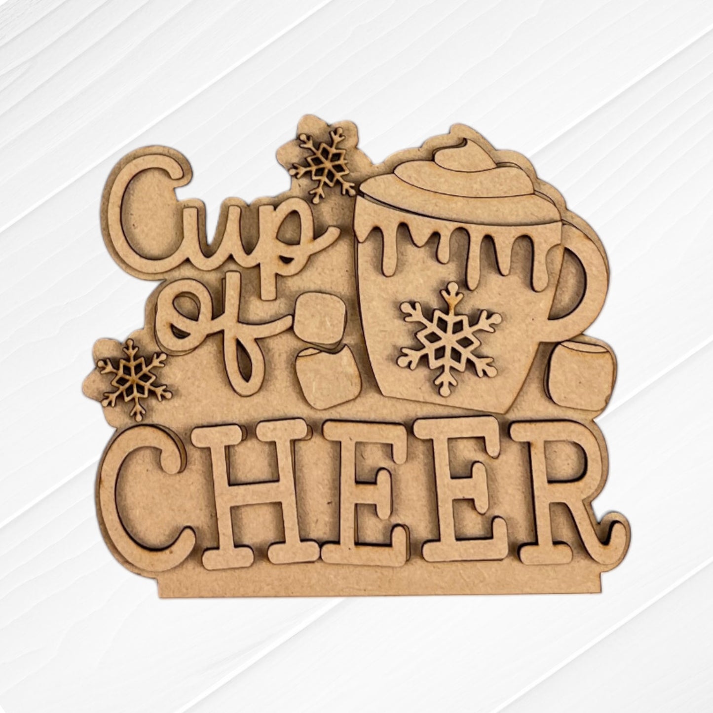 This delightful home décor item from Janet's Craft Corner, called the "Cup of Cheer Hot Cocoa Decor Set - Set of 5," showcases a wooden plaque inscribed with "Cup of Cheer." It features a mug adorned with whipped cream and a snowflake motif, embellished with small snowflake and marshmallow decorations against a white wooden backdrop, making it an ideal addition to any hot cocoa décor ensemble.