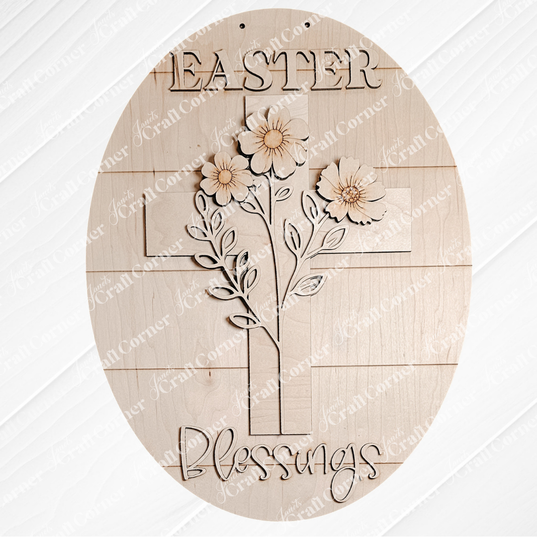 The Easter Blessings Door Hanger from Janet's Craft Corner is a charming wooden oval sign ideal for DIY seasonal decor. It features "Easter Blessings" with a stylish central cross, adorned with flowers and leaves against a light wood texture, resembling delicate cut-outs.