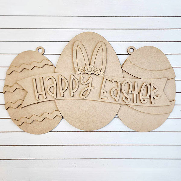 The Easter Egg Sign from Janet's Craft Corner is a charming DIY seasonal home decor craft kit featuring three eggs on a striped background. The centerpiece has bunny ears and a floral headband with "Happy Easter" beautifully written, perfect for adding festive charm to your home.