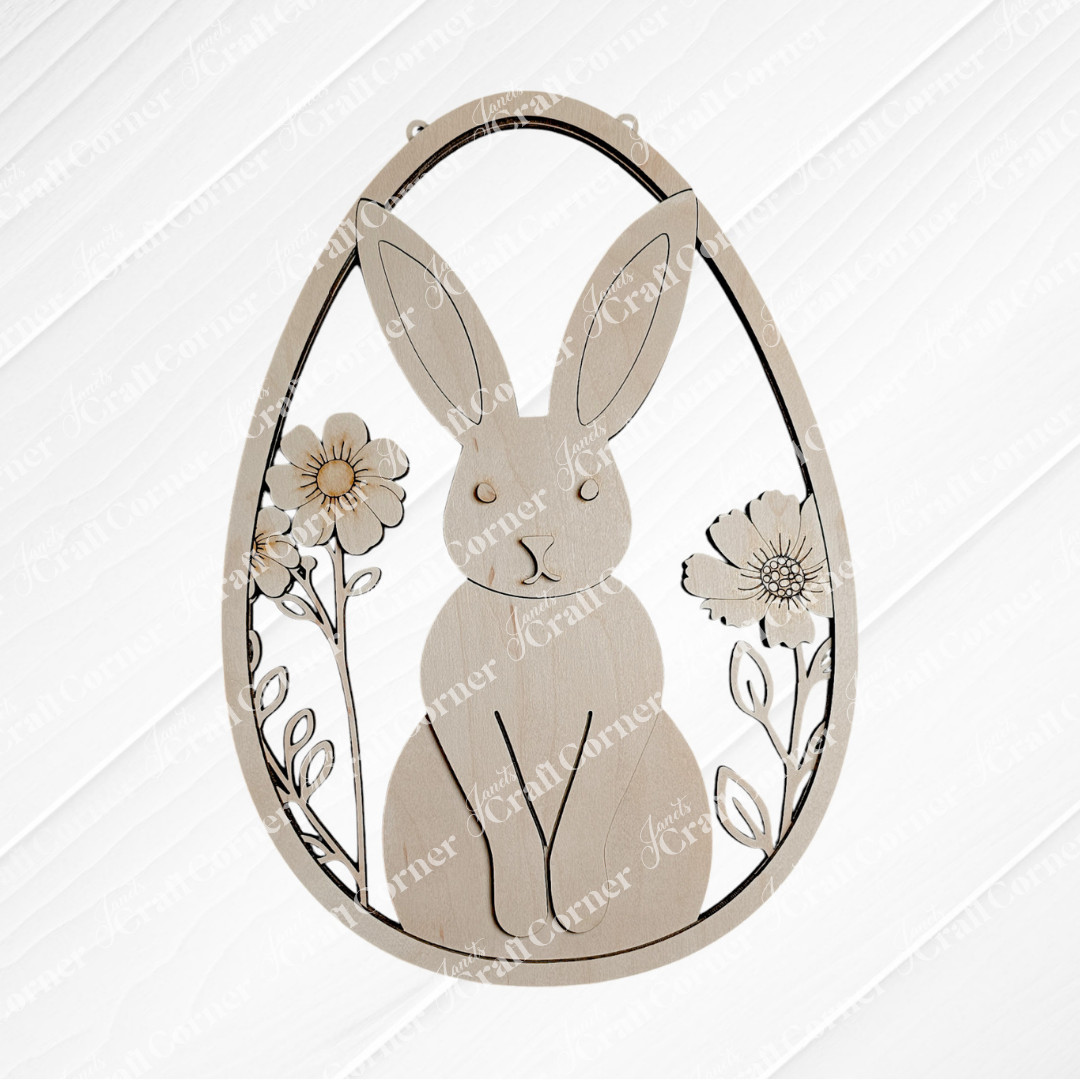 The Easter Egg Wall Hanger from Janet's Craft Corner features a wooden ornament with a cut-out rabbit amid flowers. Ideal for DIY seasonal decor, the egg-shaped kit includes wood cut-outs with a textured background.