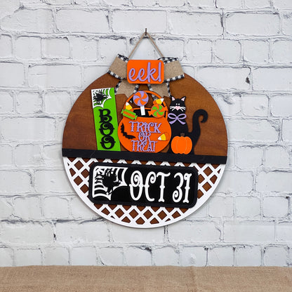 The DIY Door Hanger Interchangeable Base from Janet's Craft Corner is perfect for Halloween décor. It features a pumpkin, black cat, and phrases like "EEK!" and "Trick or Treat" against a brick background, with "Oct 31" displayed. Ideal for creative enthusiasts.