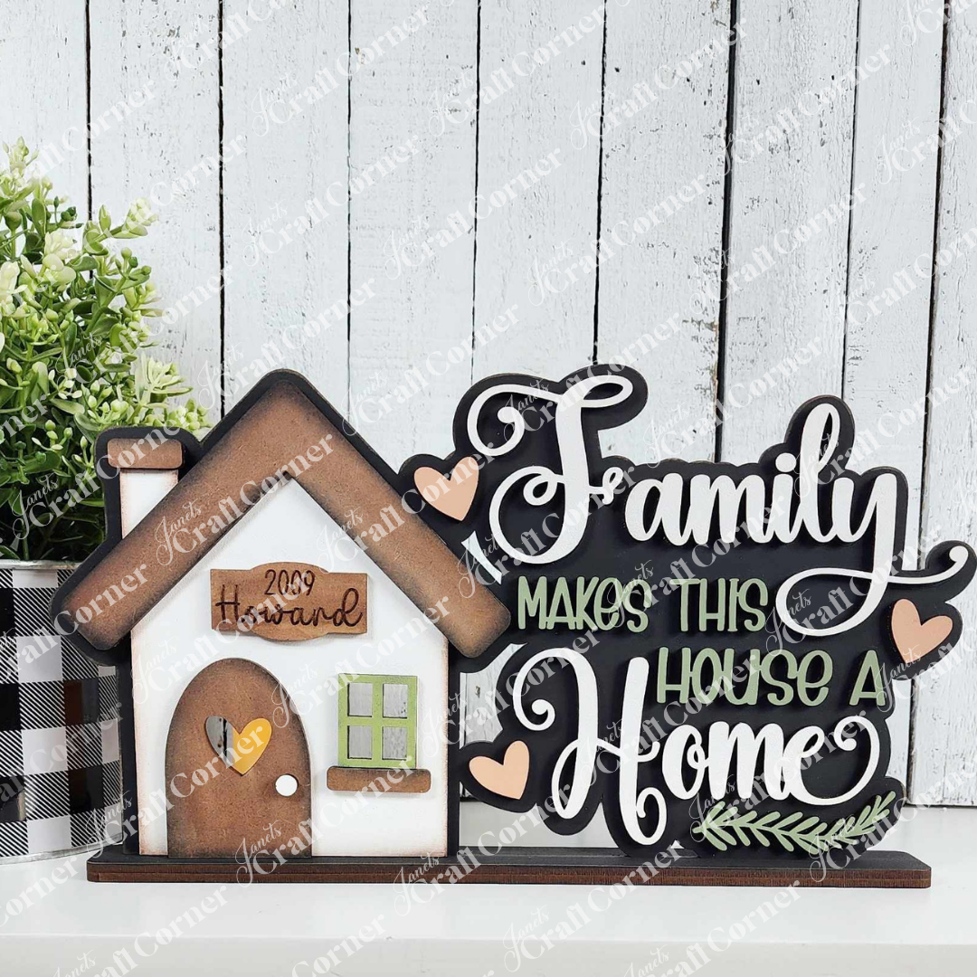 The DIY craft kit from Janet's Craft Corner transforms a small house sign with "2009 Howard" and "Family makes this house a home." Paired with a checkered pot plant against a white wall, the Family Home Word Art Votive Holder Shelf Sitter adds charm to your decor.