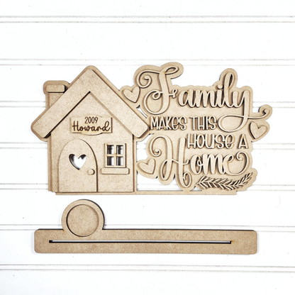 The "Family Home Word Art Votive Holder Shelf Sitter" from Janet's Craft Corner is a charming DIY decor kit. It features an ornate "Family Makes This House a Home" design, heart cutout, and a detachable strip with "2009 Howard," perfect for adding personalized charm to your home.