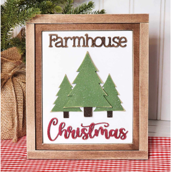 The Farmhouse Christmas Interchangeable Sign from Janet's Craft Corner is a DIY home decor craft kit that features three green trees set within a wooden frame. The word "Farmhouse" elegantly tops the sign, with "Christmas" artistically scripted in red cursive beneath. Completing this charming piece, a burlap-wrapped plant serves as the backdrop, enhancing its festive appeal.