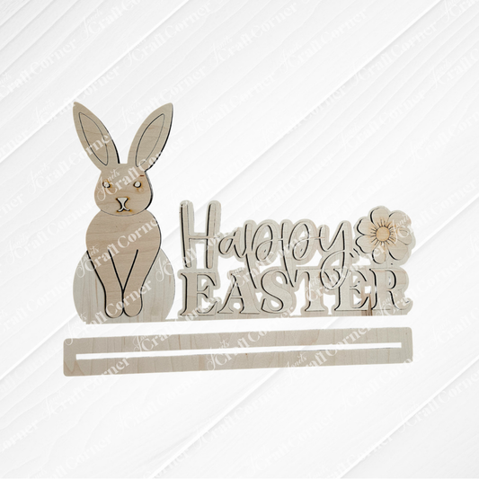 The Happy Easter Shelf Sitter from Janet's Craft Corner boasts a wooden rabbit beside "Happy Easter," intricately carved and adorned with a flower. It's ideal for seasonal decor, set against a textured white background to add elegance to your festivities.