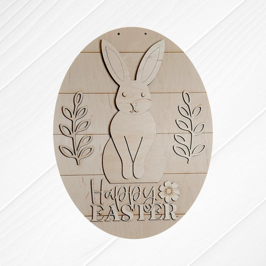 The Happy Easter Door Hanger from Janet's Craft Corner is a DIY home decor piece featuring a carved rabbit and floral designs. It has "Happy Easter" text at the bottom, is oval-shaped with a white, textured background—ideal for any wood cut-out collection.