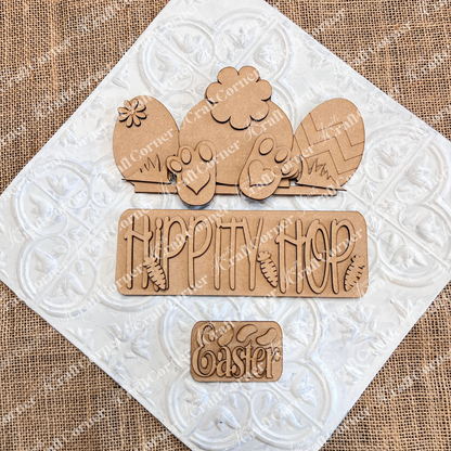 The "Hippity Hop Bunny Butt Interchangeable Insert" by Janet's Craft Corner is a charming hand-painted Easter sign on burlap featuring a bunny, patterned eggs, "HIPPITY HOP" with carrots, and "Easter" on a white diamond texture, perfect for DIY crafters seeking versatile home decor.