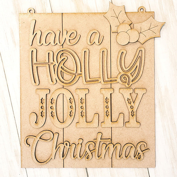 The Holly Jolly Christmas Sign from Janet's Craft Corner is a DIY kit featuring "have a HOLLY JOLLY Christmas" in various fonts, accented with holly and berries on light wood, ideal for festive home décor.