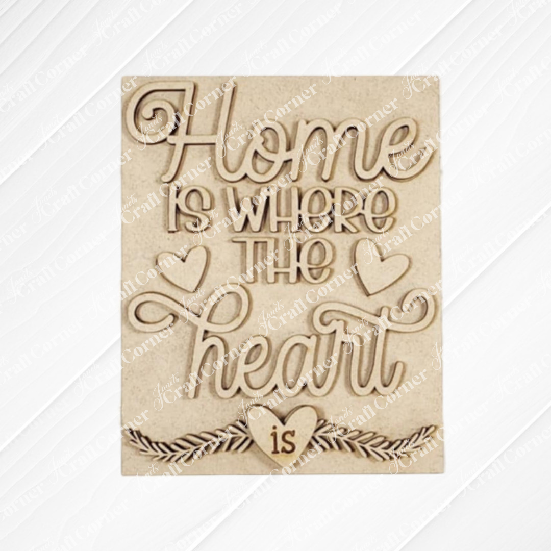 The "Home Heart Interchangeable Sign" by Janet's Craft Corner features a cursive "Home is where the heart is" quote with heart motifs on a light wooden texture, ideal for DIY home décor projects.