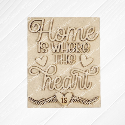 The "Home Heart Interchangeable Sign" by Janet's Craft Corner features a cursive "Home is where the heart is" quote with heart motifs on a light wooden texture, ideal for DIY home décor projects.