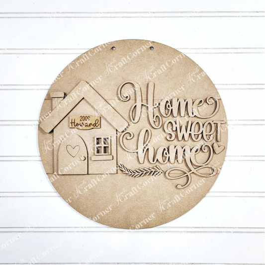 The "Home Sweet Home Door Round" by Janet's Craft Corner is a round wooden plaque for home décor. It features the text "Home Sweet Home," a house design with a heart, and "200 Howard" on a white panel, making it ideal as a DIY craft kit to personalize any living space.