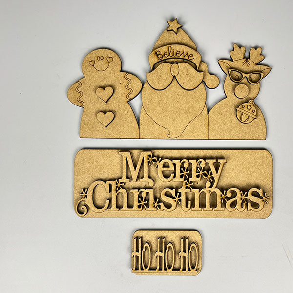 The Merry Christmas Interchangeable Insert from Janet's Craft Corner features wooden cutouts for DIY home decor, including a gingerbread figure, Santa with a "Believe" hat, a reindeer with sunglasses and a bauble, along with "Merry Christmas" and "Ho Ho Ho" plaques—ideal for your hand-painted projects on a simple background.