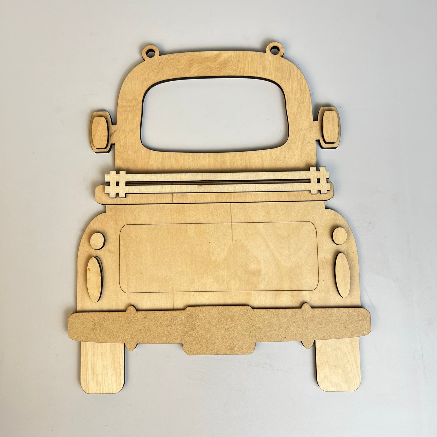 Introducing the "Antique Truck Base with Interchangeable Insert" — a DIY home decor kit by Janet's Craft Corner. This hand-painted set includes a wooden cutout of an antique truck seen from the rear, complete with wheels, a rear window, side mirrors, and lights. The simple yet elegant design features distinct outlines, allowing you to customize your creation with interchangeable inserts.