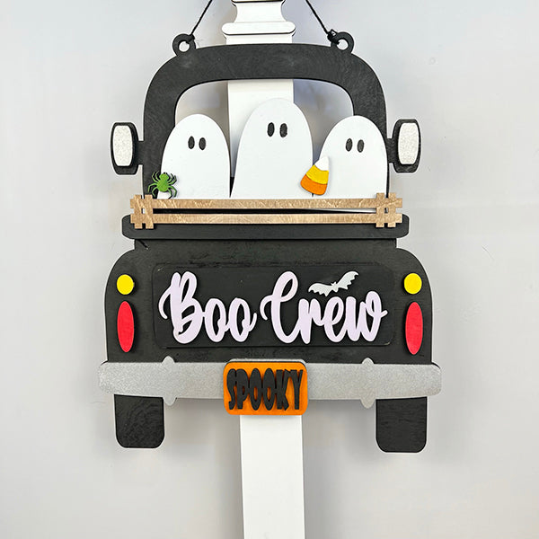 The Boo Crew Interchangeable Insert by Janet's Craft Corner features a black truck with three white ghosts in the back; one ghost has candy corn, another holds a green spider. "Spooky Sidekicks" come to life with "Boo Crew" on the truck and "Spooky" below, all on a white background.