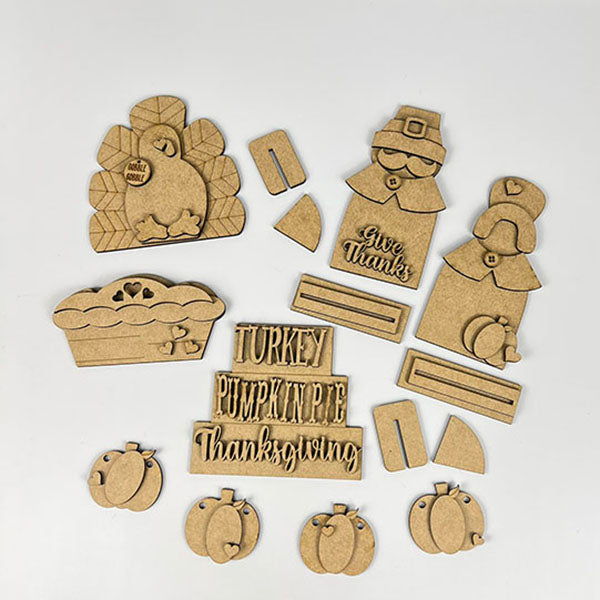 Janet's Craft Corner offers the "Give Thanks Decor Set," a 6-piece DIY kit ideal for Thanksgiving tiered trays. It includes unpainted wooden pieces: a turkey, pilgrim couple with "Give Thanks," a pie, and words like "Turkey" and "Pumpkin Pie" for festive home décor.