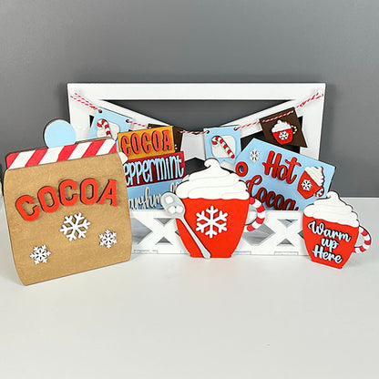 Janet's Craft Corner presents the Hot Cocoa Tiered Tray Pieces, a DIY Kit featuring cocoa-themed decorations with signs labeled "Cocoa," "Peppermint," and "Hot Cocoa." The set includes red mugs adorned with whipped cream and candy canes, along with snowflake embellishments—all arranged against a gray and white backdrop to create the ideal holiday décor.