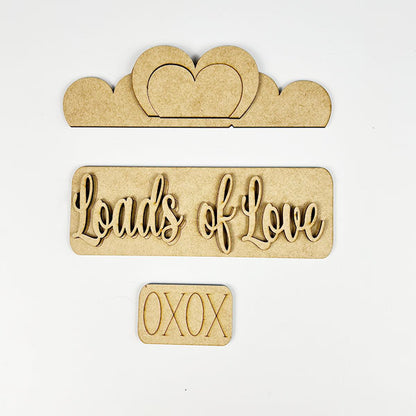 Explore the delightful Loads of Love Interchangeable Insert DIY home decor kit by Janet's Craft Corner. This kit includes wooden pieces that elegantly spell out "Loads of Love" and "XOXO" in cursive, along with a cloud-shaped piece featuring a heart cutout. It's ideal for adding a personal touch to any plain background.