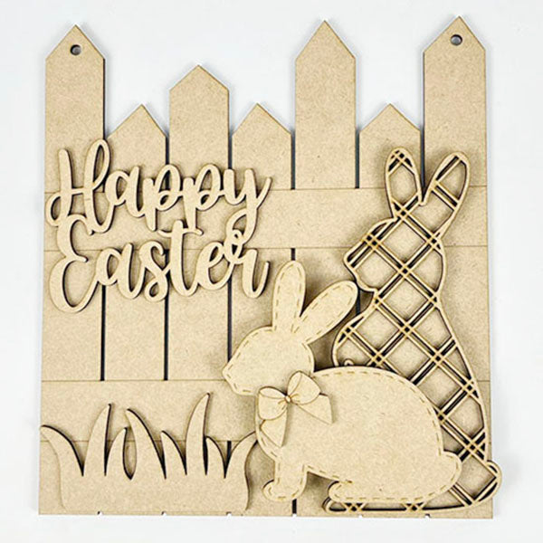 The Easter Picket Fence Door Hanger from Janet's Craft Corner is a delightful DIY craft kit featuring two vintage-style bunny cutouts with floral designs and "Happy Easter" text. These charming rabbits stand against a picket fence backdrop, complete with grass details.