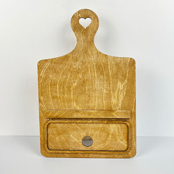 The Breadboard Interchangeable Base with Insert by Janet's Craft Corner features a handle with a heart-shaped cutout and a built-in drawer with a silver knob, finished in natural wood. Ideal for home décor, it’s set against a white background, ideal as part of their DIY home decor kit.