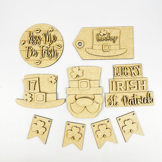 The St Patricks Decor Set by Janet's Craft Corner is a DIY craft kit including six wooden pieces such as shamrocks and leprechaun hats, with festive phrases like "Kiss Me I'm Irish." It features banners, a round piece, and a tag designed for any Tiered Tray Kit.