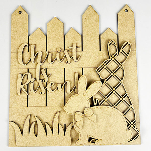 Enhance your Easter decor with Janet's Craft Corner's "He is Risen" Picket Fence Door Hanger. This DIY craft kit features two bunny silhouettes—one in plaid, the other with a bow tie—and a wooden fence backdrop inscribed with "Christ is Risen," perfect for adding festive charm to your home.