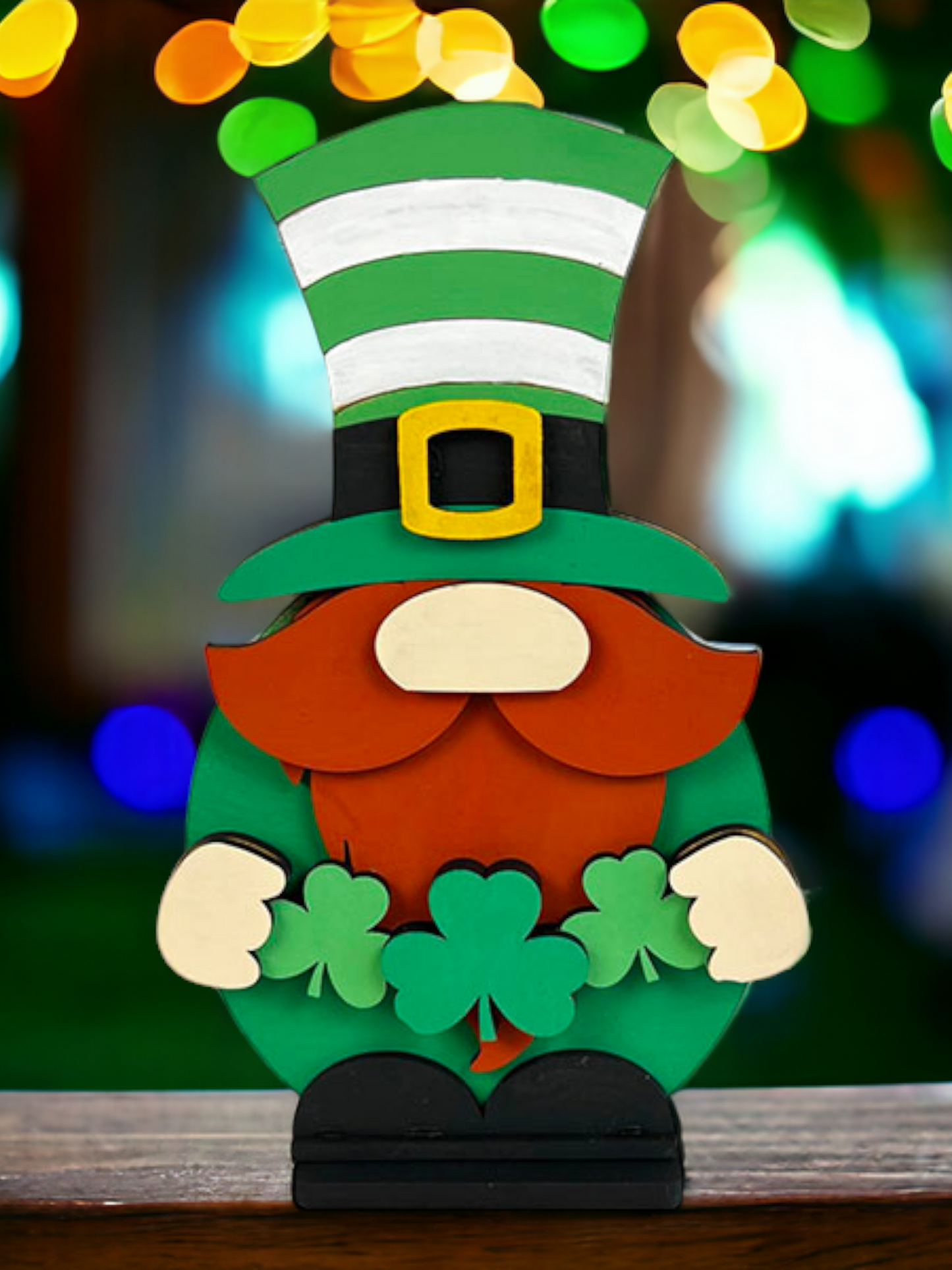 Janet's Craft Corner offers a Leprechaun Gnome Shelf Sitter DIY kit. This whimsical wooden figure has an orange beard, green clothes, a striped hat, and holds three shamrocks. A festive décor piece that brightens any space with its charm! Ideal for those who love holiday cheer.