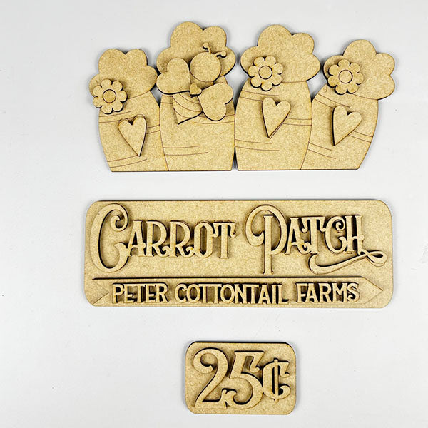 The Carrot Patch Interchangeable Insert DIY home decor kit from Janet's Craft Corner features wooden craft pieces ideal for home decor or DIY projects, including three vases adorned with flowers and hearts, a "Carrot Patch Peter Cottontail Farms" sign, and a "25¢" label. Use these adaptable pieces to keep your space looking fresh and festive.