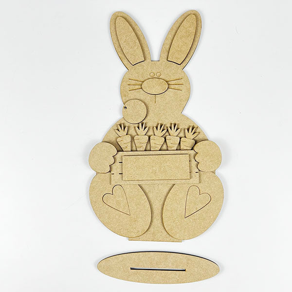 Add spring cheer with Janet's Craft Corner's Carrot Patch Bunny Shelf Sitter, a charming unpainted bunny-shaped holder featuring cutouts and a rectangular sign with five carrots, all on an oval base. Ideal for Easter decor and seasonal DIY crafts.