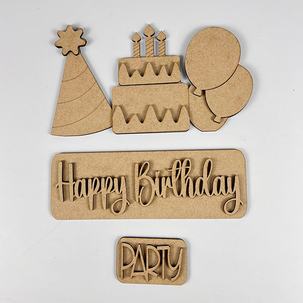 Various wooden cutouts including a party hat, a birthday cake with candles, balloons, and the words "Happy Birthday" and "Party" from Janet's Craft Corner are beautifully displayed on a white background. These components are perfect for creating your own customized Birthday Interchangeable Insert as part of your DIY home decor projects.