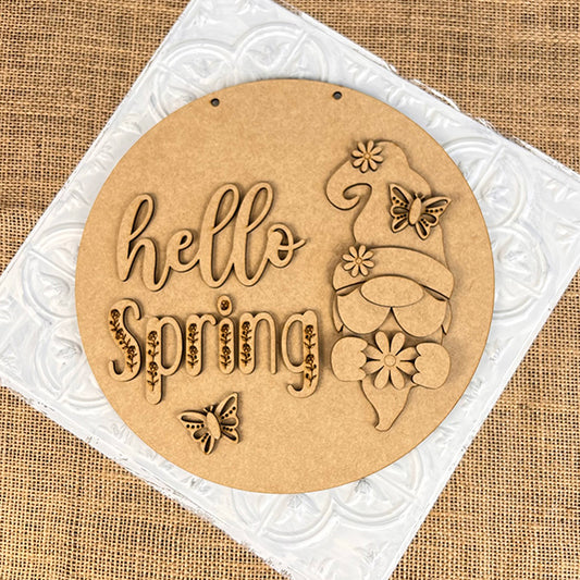 This charming Hello Spring Gnome Door Hanger from Janet's Craft Corner is a round wooden plaque ideal for home décor, featuring the text "Hello Spring" next to a carved gnome holding a flower. It is adorned with butterfly cutouts on a burlap background, creating an inviting and cheerful piece.