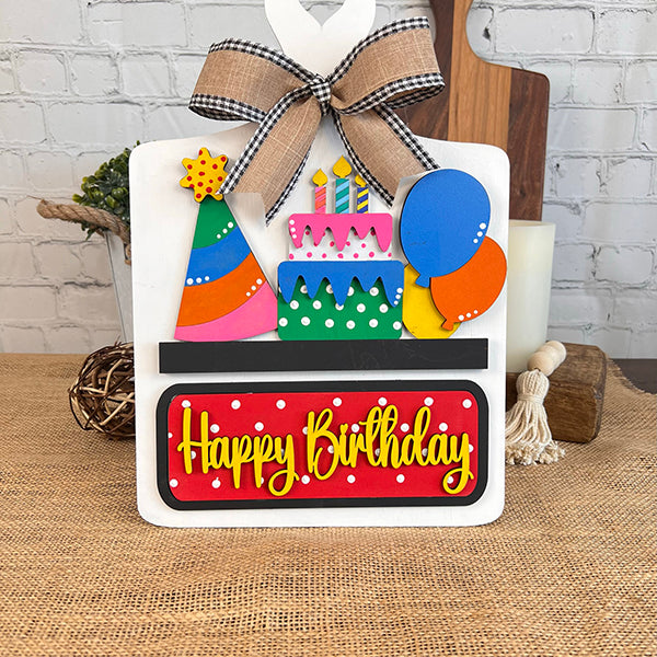 Celebrate with Janet's Craft Corner's "Birthday Interchangeable Insert," featuring a festive DIY Craft Kit. Create your own personalized card complete with a 3D layered cake adorned with candles, a colorful party hat, and balloons. The kit includes a bow-topped card set against a burlap and white brick background, perfect for crafting unique birthday greetings.