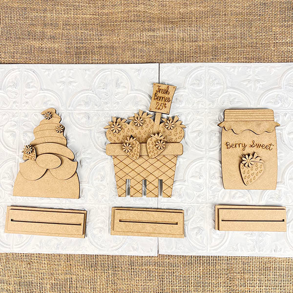 Janet's Craft Corner presents the Strawberry Mini Shelf Sitters DIY seasonal home decor craft kit. Set of 3 includes a tiered display, mini signs, and a basket with "Fresh Berries 25¢" sign on textured white tile. Each piece features farmhouse chic strawberry-themed decor with matching bases.